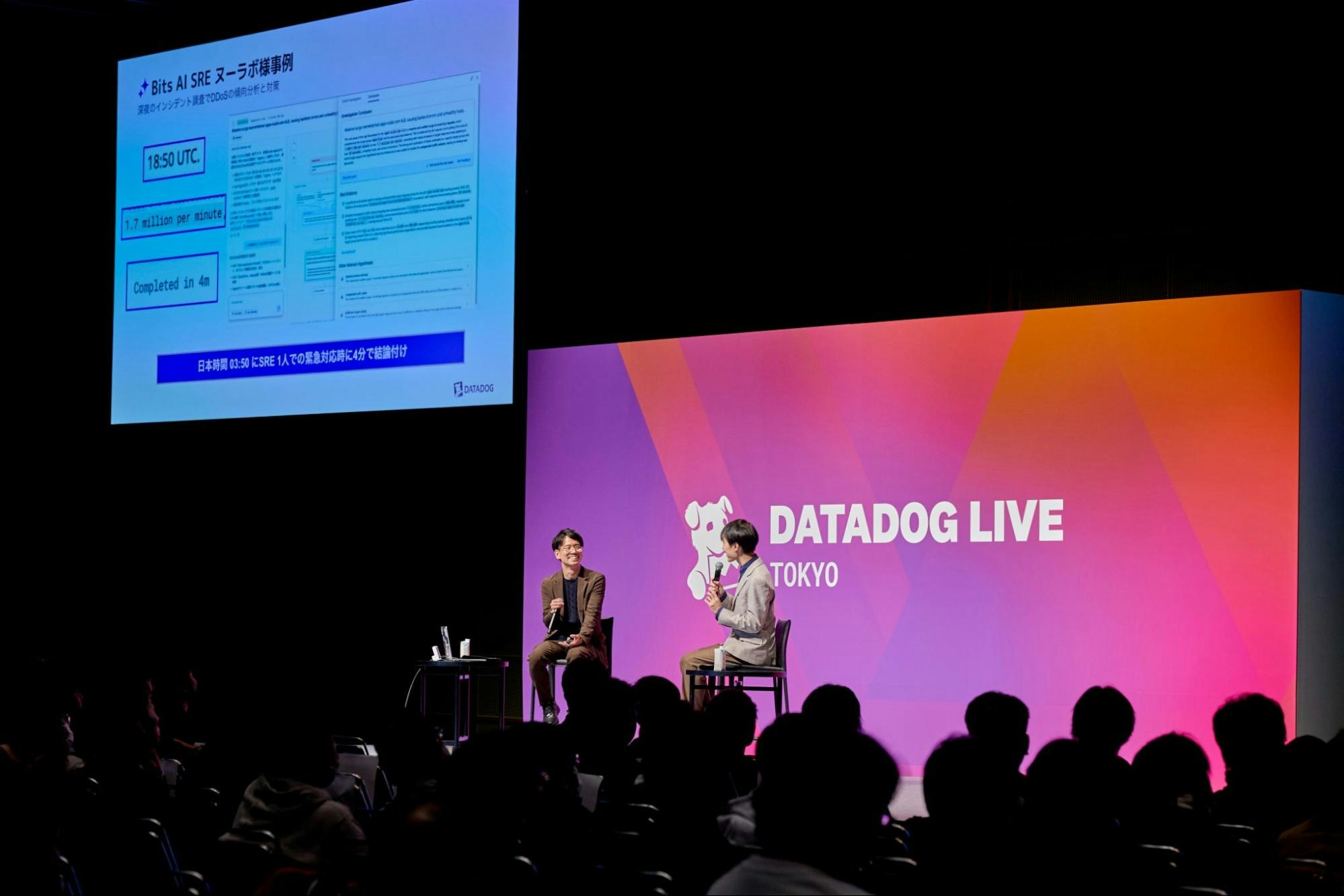 Datadog Live Tokyo 2025 にて、登壇者がステージ上でBits AI SRE に関するスライドを表示しながら対談する様子。 Datadog Live Tokyo 2025 にて、登壇者がステージ上でBits AI SRE に関するスライドを表示しながら対談する様子。