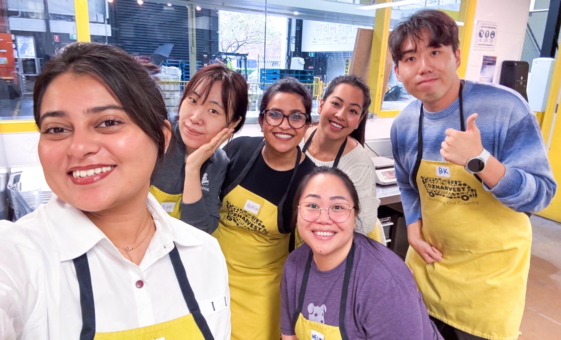 Datadog employees volunteering at a food bank, wearing yellow aprons and smiling for the camera