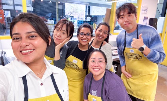 Datadog employees volunteering at a food bank, wearing yellow aprons and smiling for the camera